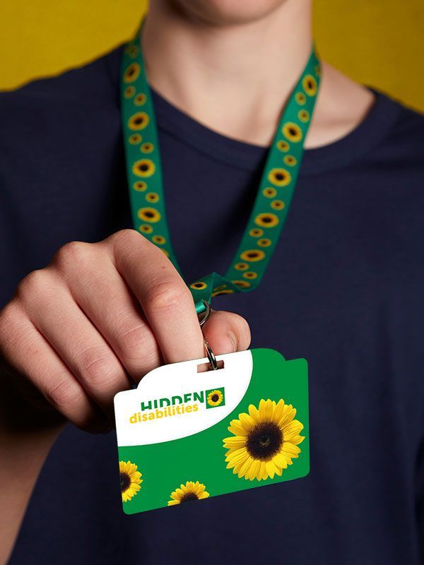 Young man wearing a dark blue t-shirt, a green Sunflower lanyard and holding a Sunflower ID card