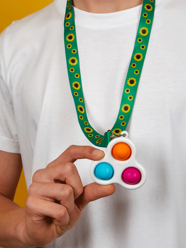 Blue, pink and orange bubble fidget toy held by hand off a green and yellow Sunflower lanyard 